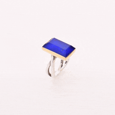 Handmade sterling silver and gold ring with doublet made of crystal quartz and lapis lazuli gemstones, in a parallelogram shape. The band of the ring is made of sterling silver and the outline of the bezel is made of 18 carats gold. The doublet consists of two layers of stones. The upper stone is crystal quartz and the stone at the bottom is lapis lazuli.