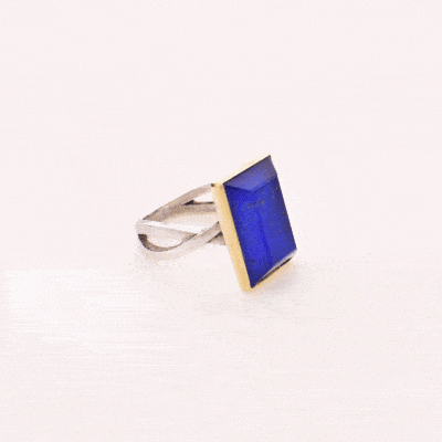 Handmade sterling silver and gold ring with doublet made of crystal quartz and lapis lazuli gemstones, in a parallelogram shape. The band of the ring is made of sterling silver and the outline of the bezel is made of 18 carats gold. The doublet consists of two layers of stones. The upper stone is crystal quartz and the stone at the bottom is lapis lazuli.