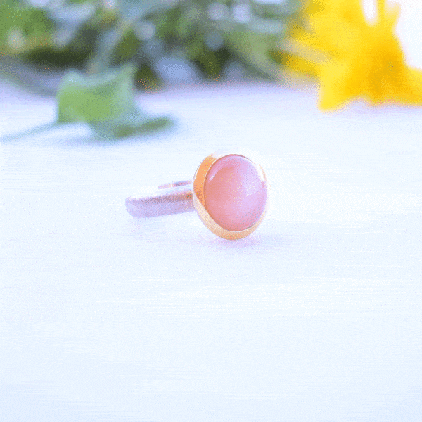 Handmade ring made of sterling silver with natural peach moonstone in a round shape. The ring features a textured band and gold-plated bezel setting for a unique, luxurious finish.