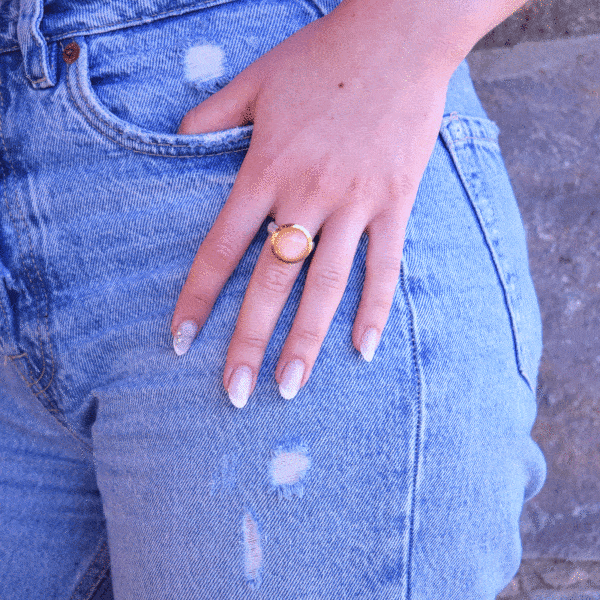 Handmade ring made of sterling silver with natural peach moonstone in a round shape. The ring features a textured band and gold-plated bezel setting for a unique, luxurious finish.