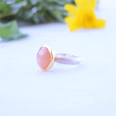 Handmade ring made of sterling silver with natural peach moonstone in a round shape. The ring features a textured band and gold-plated bezel setting for a unique, luxurious finish.