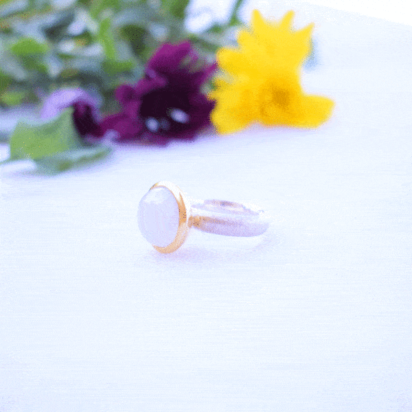 Handmade ring made of sterling silver with natural white labradorite gemstone in a round shape. The ring features a textured band and gold-plated bezel setting for a unique, luxurious finish.