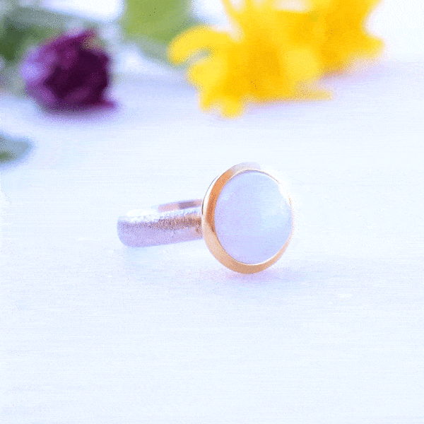 Handmade ring made of sterling silver with natural white labradorite gemstone in a round shape. The ring features a textured band and gold-plated bezel setting for a unique, luxurious finish.